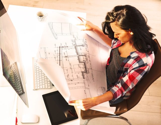 mulher a olhar para uma planta de construção